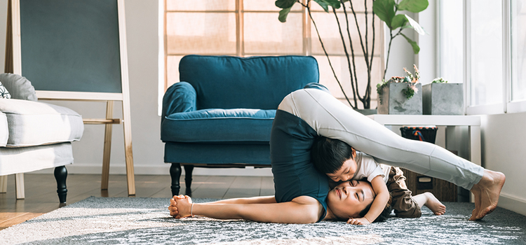 A mom doing yoga while her child playfully rests on her face as an example of lifestyle photography