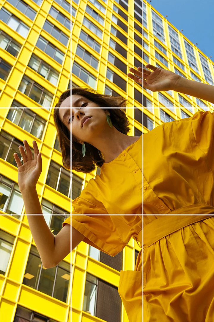 A photo looking up at a person wearing a yellow romper while standing in front of a building