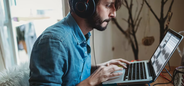 A guy using Adobe Audition to convert an audio file on his laptop