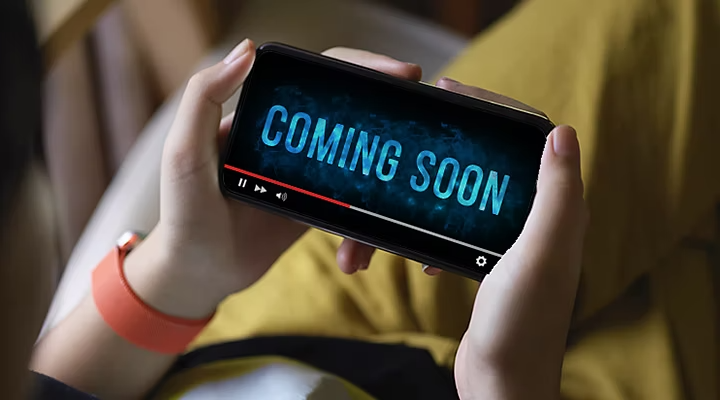 A person holding their phone and watching a film trailer