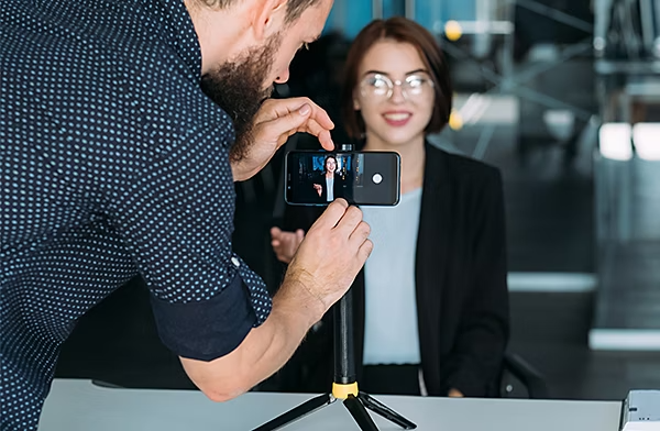 A person setting up a mobile phone on a tripod to record a video