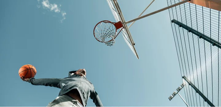 Low-angle camera shot of a man dunking a basketball.