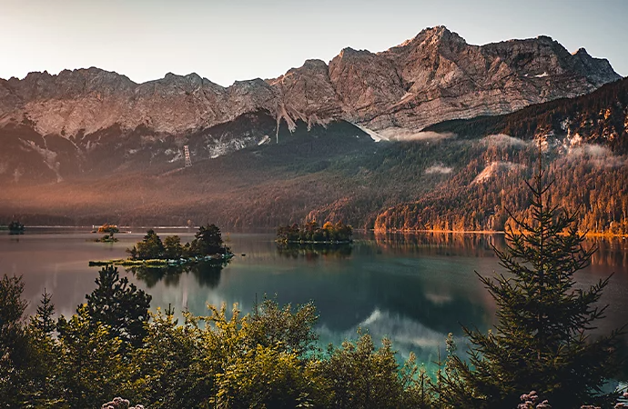 A lake in front of a tree and snow-covered mountain