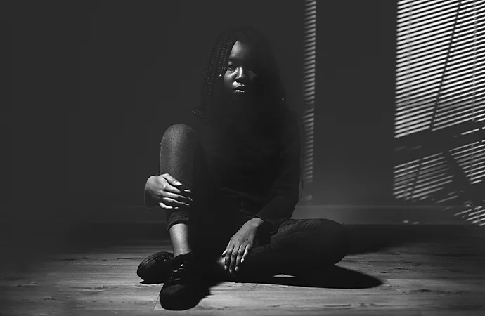 A black-and-white photo of a person sitting on the ground