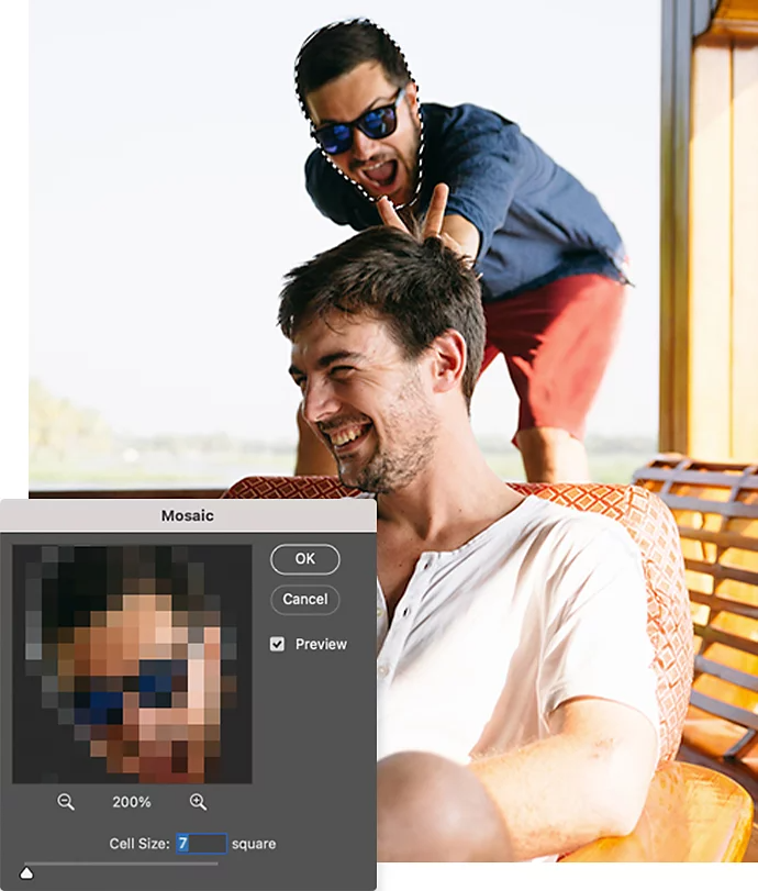 A picture of someone giving bunny ears to someone sitting in a chair with the Adobe Photoshop mosaic settings window superimposed over it