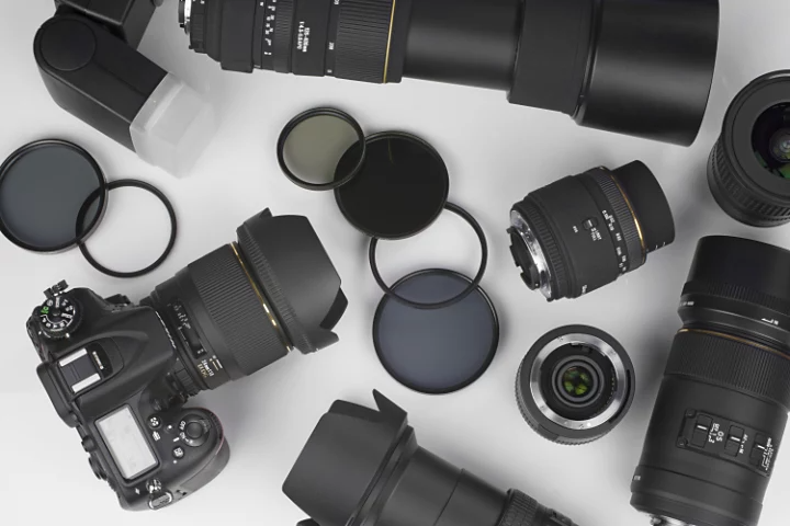 A camera next to numerous different lenses on a table