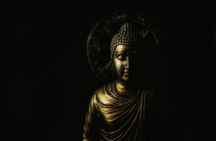 Gold spiritual statue lightly spotlighted in a completely dark area