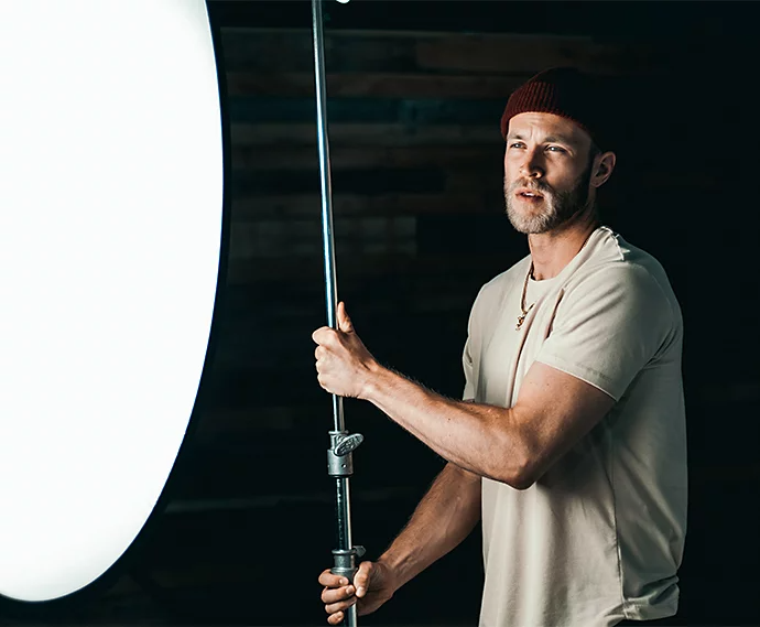 A videographer setting up a light reflector for a commercial