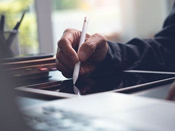 Joven ejecutivo frente a la computadora incluyendo su firma electrónica en un documento digital