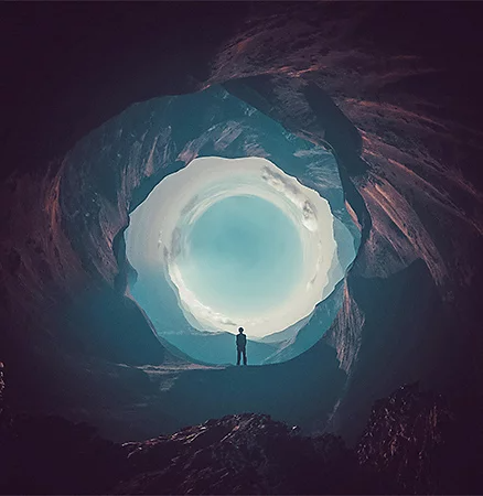 Person standing in the distance inside of rounded out cave