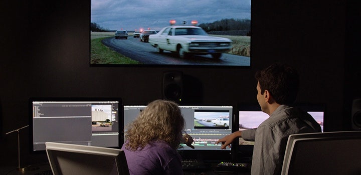 Editors in studio editing footage of a police car chase.