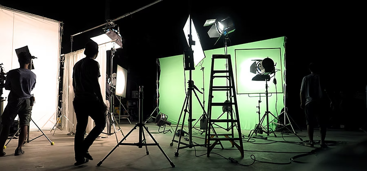 Film crew sets up the lighting of a green screen