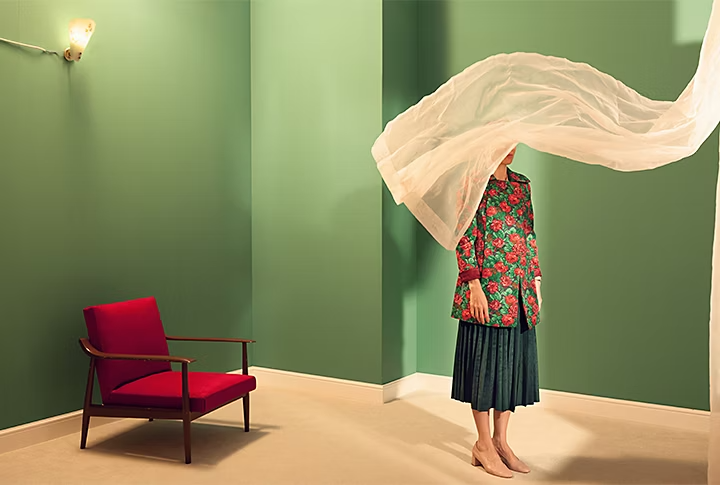 A person in a green room with a curtain blowing over them