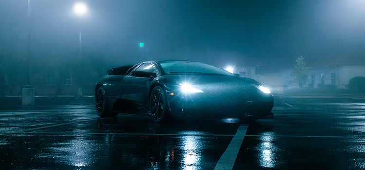 A nighttime photo of a sports car with raindrops on it