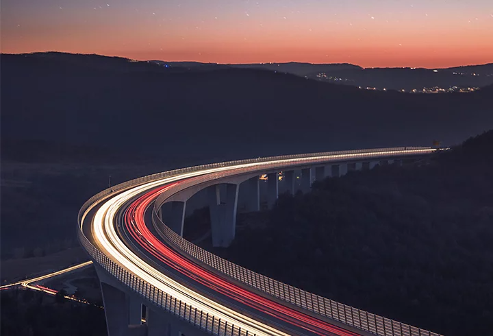 A photo taken at night of a mountain highway running through a hillside