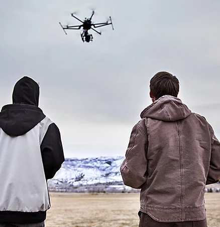 Two individuals pilot a drone with a camera in preparation for some aerial photography