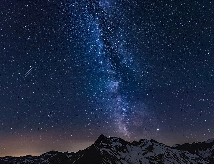 The Milky Way shining in the night sky above a snow-covered mountain captured through long-exposure