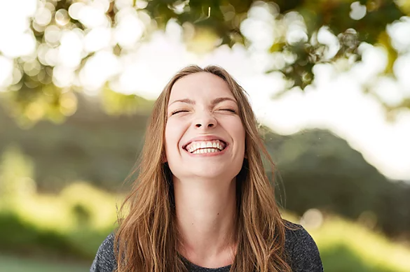 A portrait photo of a person smiling outside.