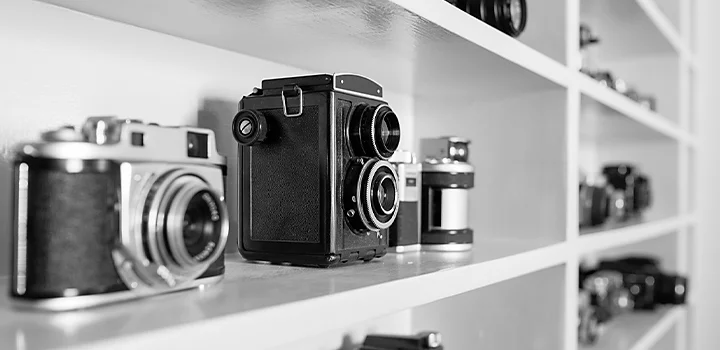 Monochrome photo of vintage cameras on a shelf