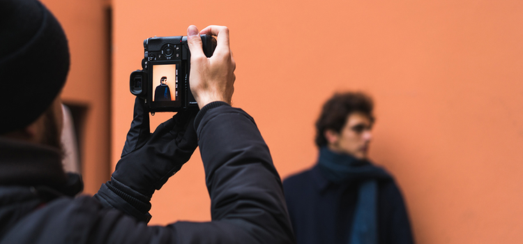 Een fotograaf maakt een foto van een model dat vóór een oranje achtergrond poseert als voorbeeld van hoe je betere foto's maakt