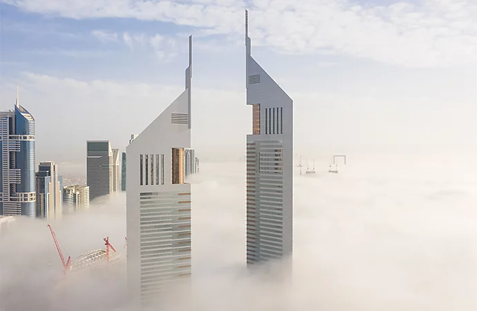 Skyscrapers rising through fog rolling through a city