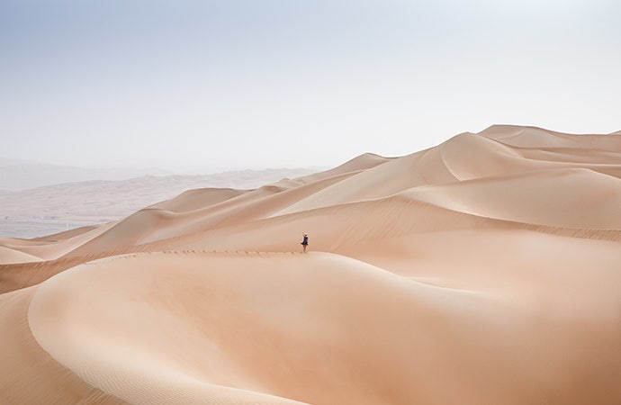 Magnificent nature photograph of a person walking on huge dunes of sand.