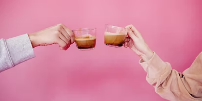 Close up of two people clinking glass mugs in a festive manner.