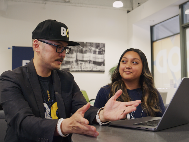 Two volunteers collaborating around a laptop