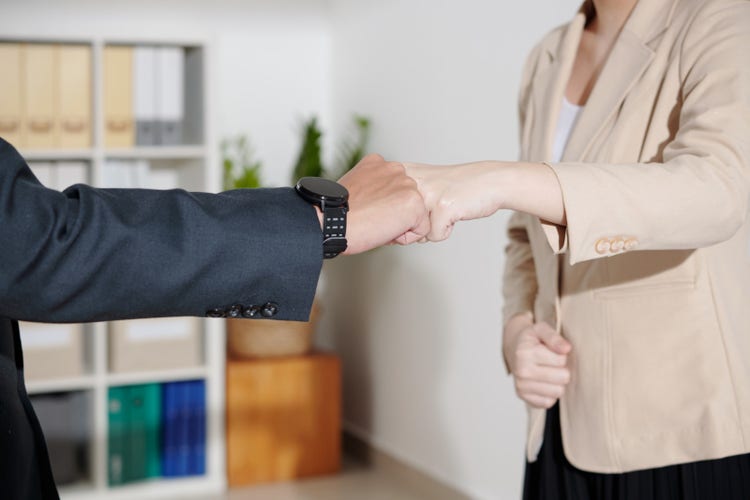 Photo of the hands and torso of two people in a handshake/fist pump in agreement.