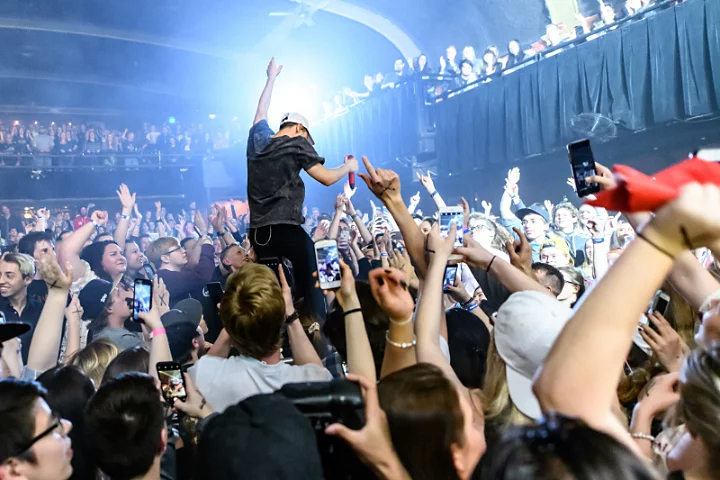 A singer standing in a crowded audience that is cheering them on