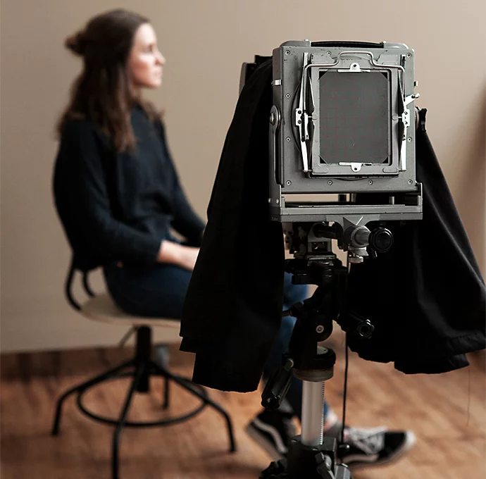 A tintype camera pointed at a person posing