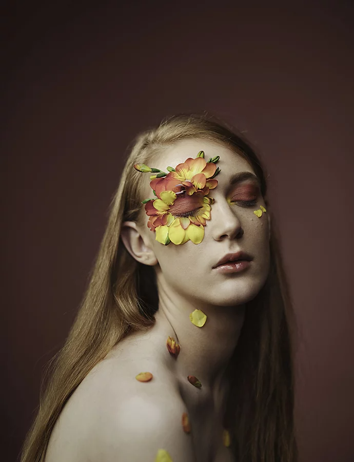 A model posing with flower petals on their face