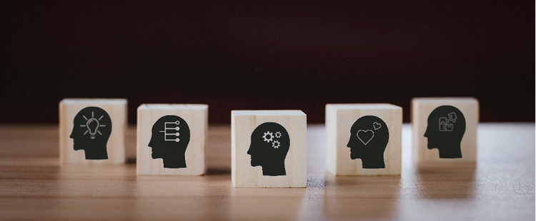 Photo of five wooden blocks with the outline of a person's head and diagrams depicting different concepts, thought processes and skills such as thinking, ideas, and emotions.