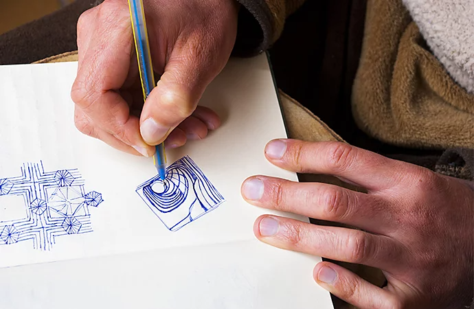 A person hand-drawing logo designs in a notebook