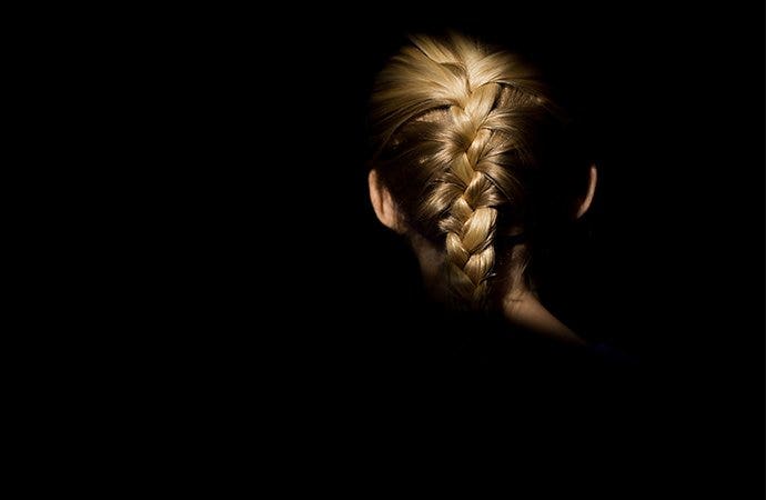 Braids on the back of someone's head spotlighted in a completely dark room