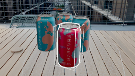 Four blue, gold and red cans depicting outlines of different countries placed on slatted table.