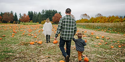A family walking through a pumpkin patch in the fall