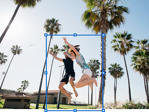 The Free Transform tool outline is used to select two adults jumping in the park next to a beach
