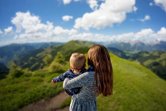 A photo of a parent holding a child on a mountain.