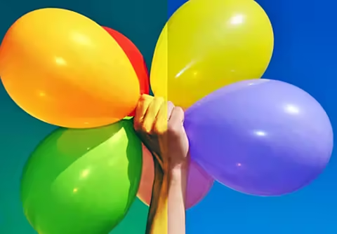An image of a hand holding balloons. The colors in half of the image are more intense than in the other half.