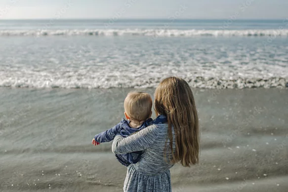 A photo of a parent holding a child at the beach.