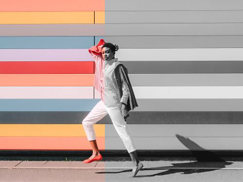 An image of a person standing against a wall. Half of the image is colorful and the other half is black and white.