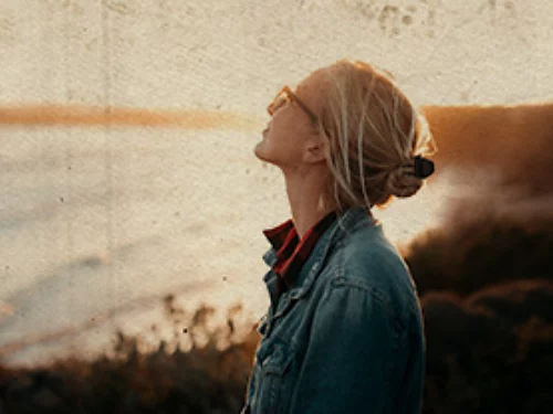 A photo of a person staring into the distance along the coast being made to look like an old photo using texture overlays