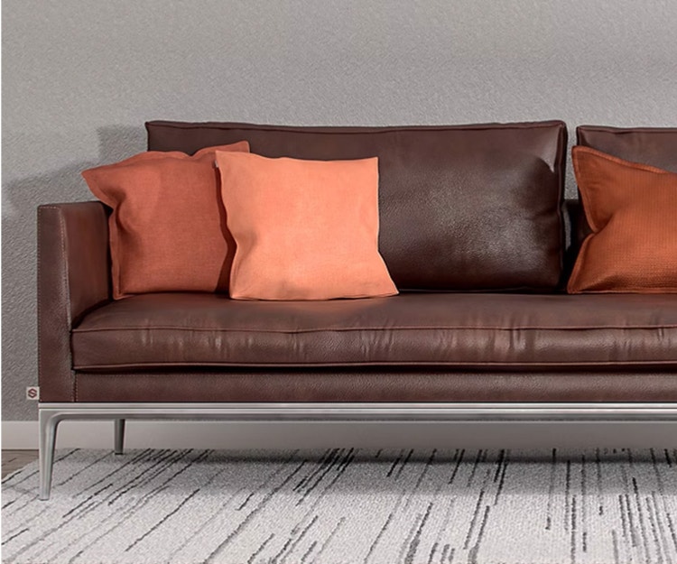 photo of a leather couch with orange pillows