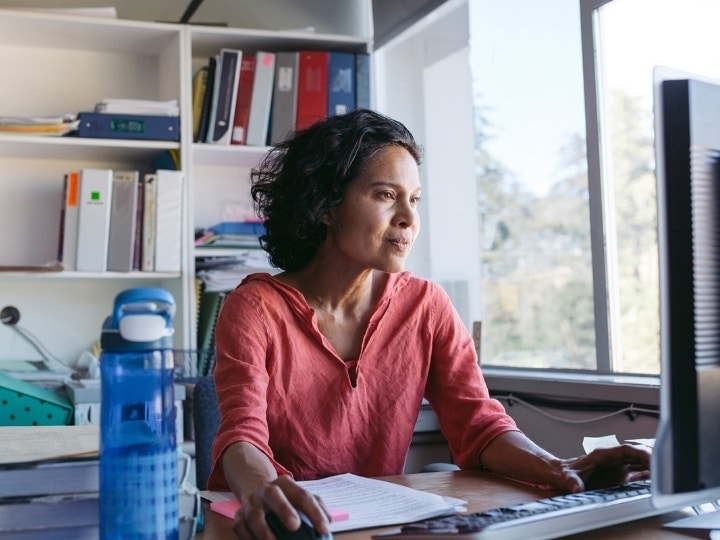 A teacher sitting at a desk using their computer to grade homework online