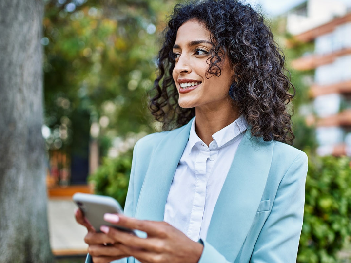 A business professional holding a smartphone looks into the distance