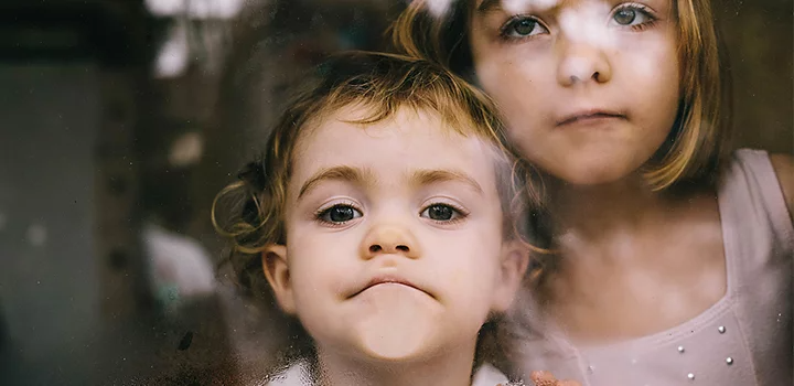 Candid photo of two children with their faces pressed up against window