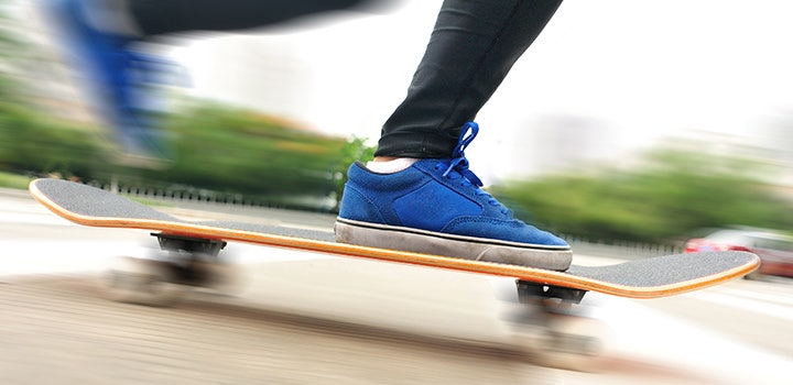 Close up photo of skateboarder’s shoes and skateboard in street with motion blur.