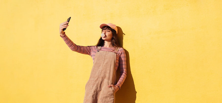 A self-portrait of a model blowing a bubble while posing for a selfie