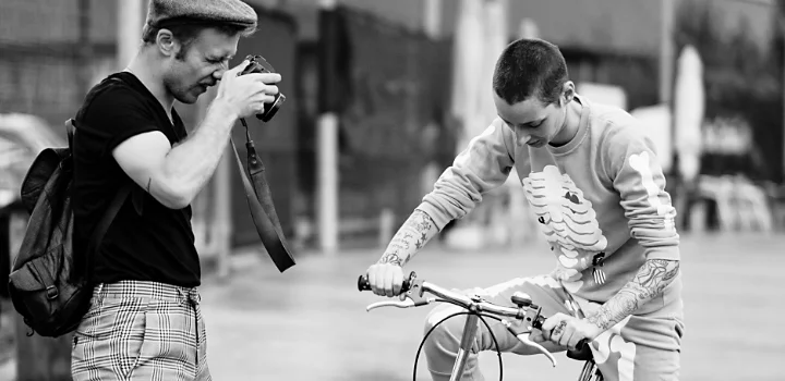 Black-and-white photo of a photographer taking a photo of a person riding a bike